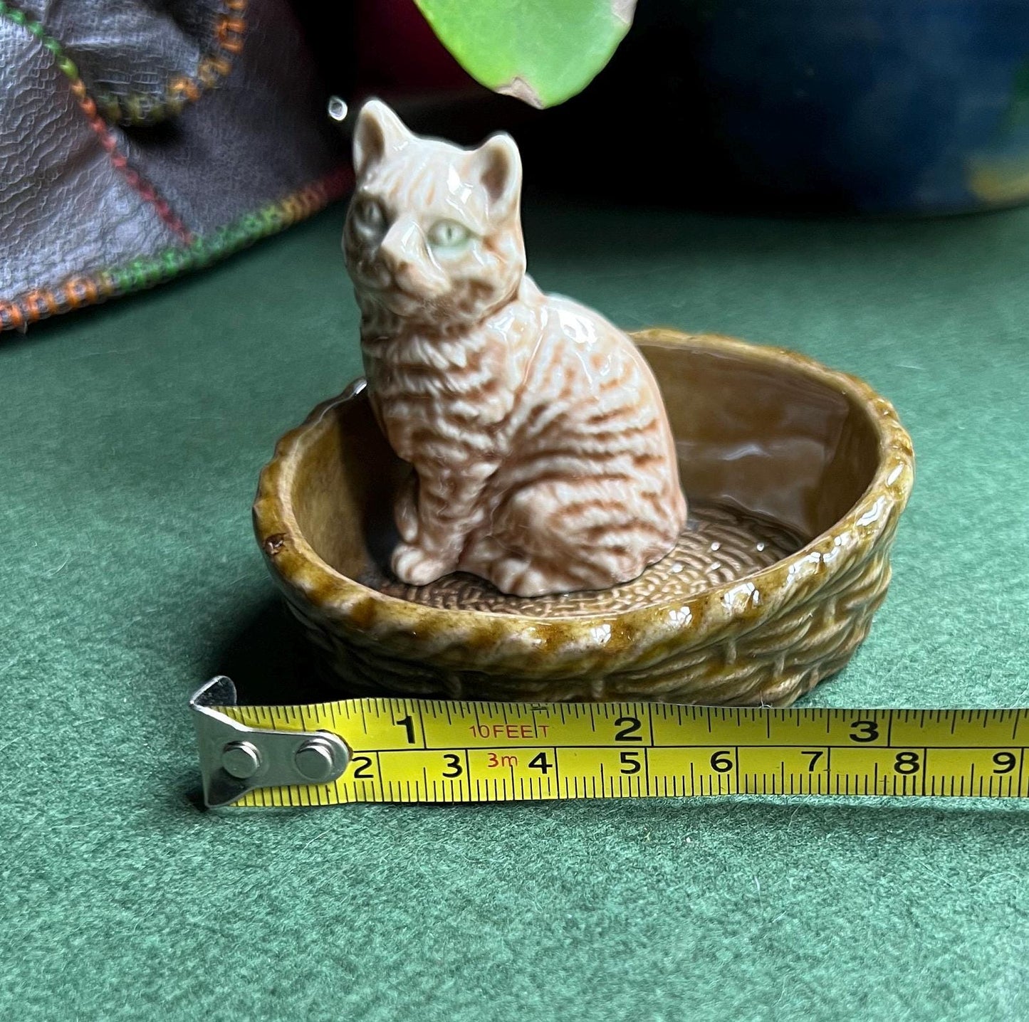 Wade tabby cat sitting in a green basket.