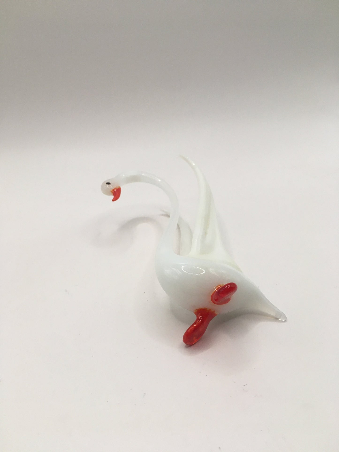 Hand blown art glass long necked white swan figurine with red beak and feet. Wings raised.