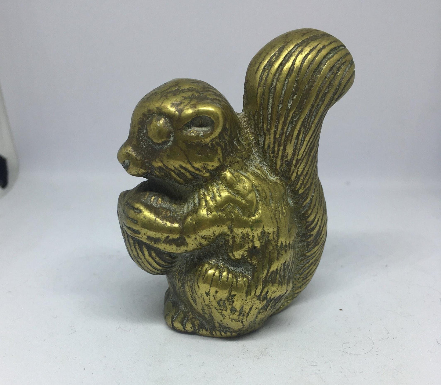 Vintage solid brass squirrel holding a nut.