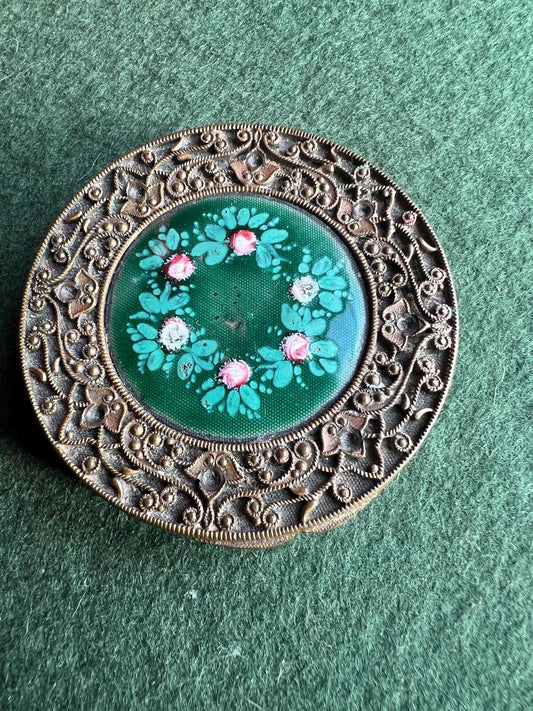 Vintage decorative compact pill box. Antique brass metal filigree with painted enamel floral detail. Lidded trinket box.