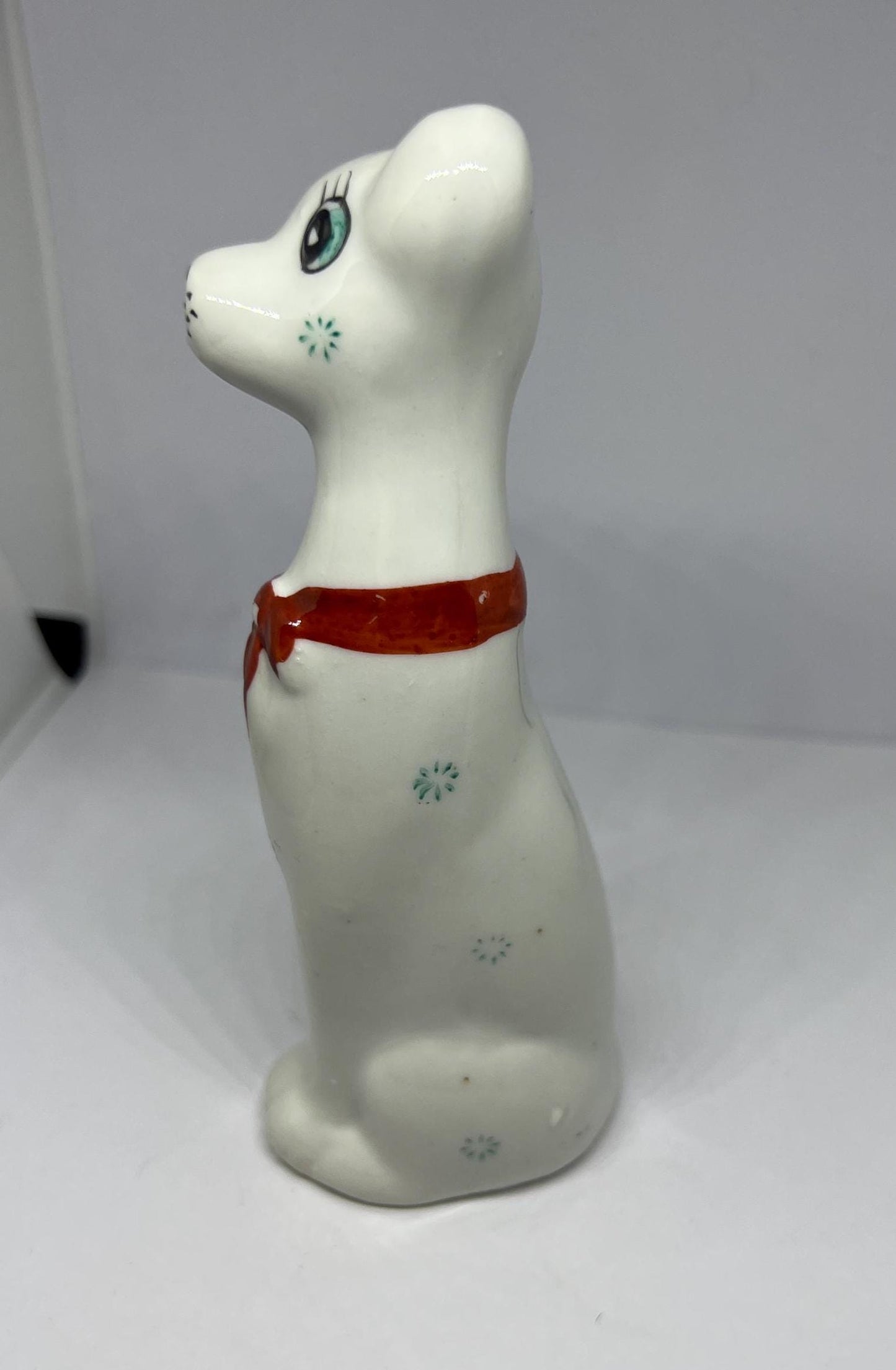 White doe eyed dog with flower spots and red scarf.