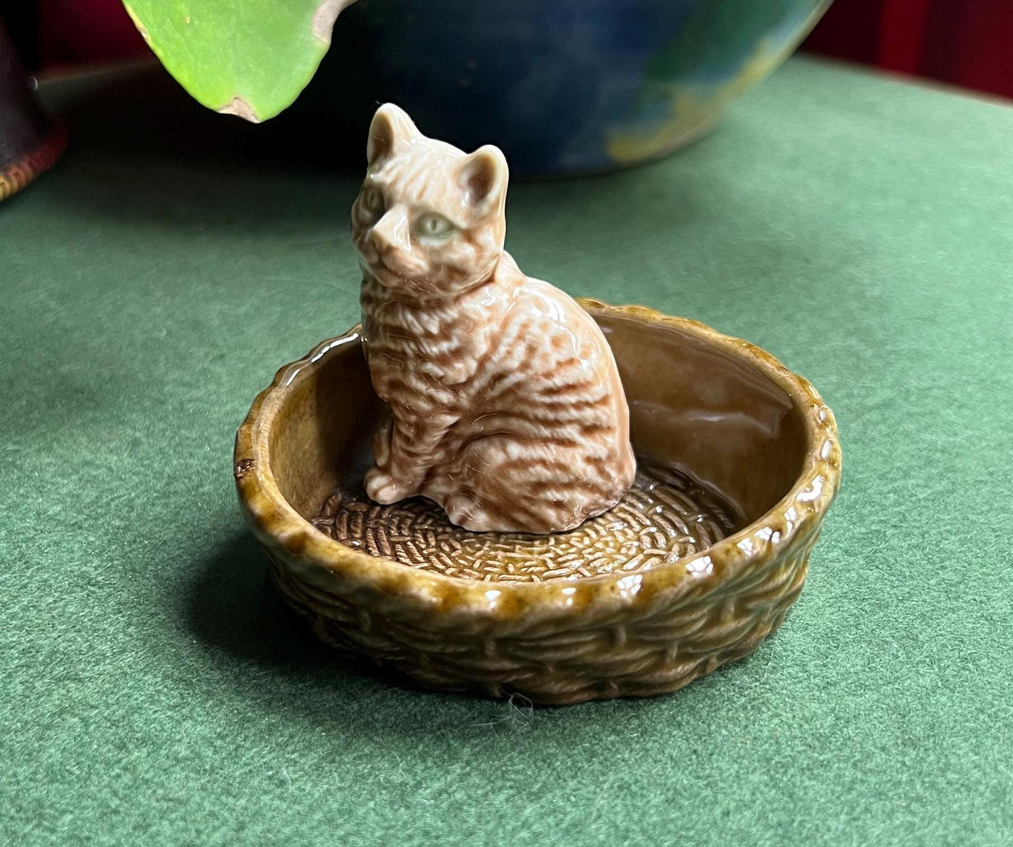 Wade tabby cat sitting in a  green basket.