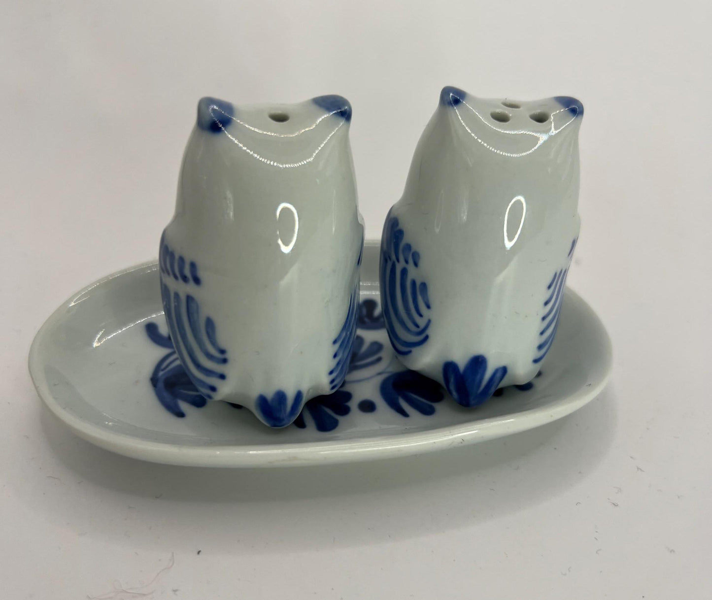 Tiny owl salt and pepper shakers on an oval plate.