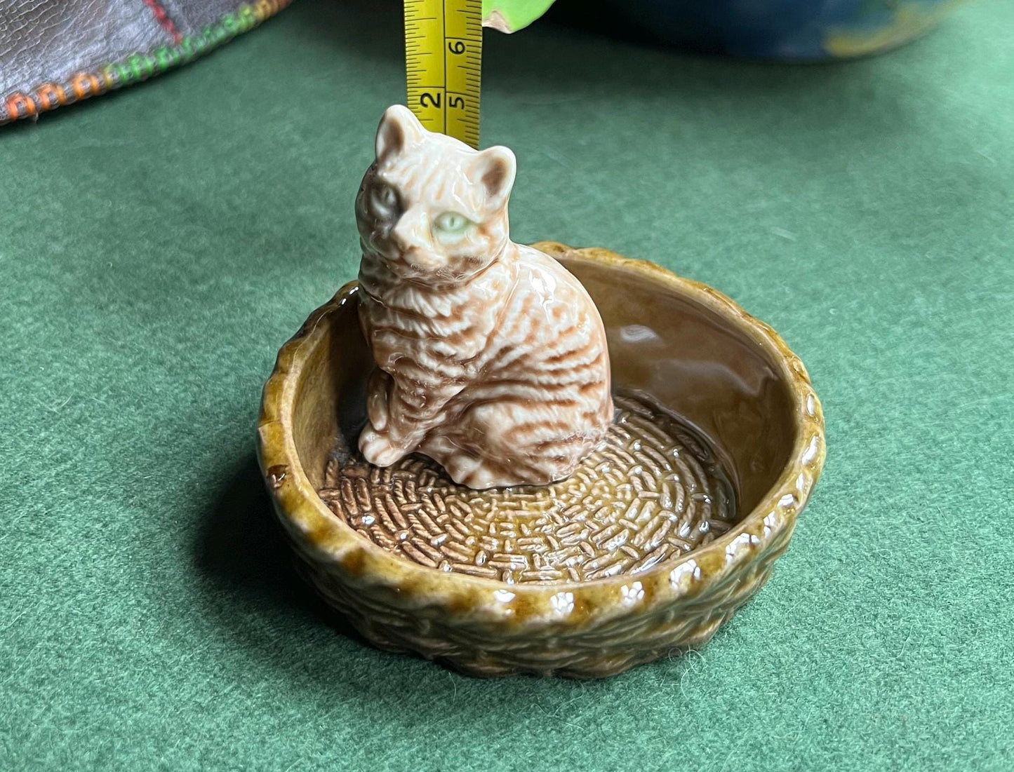 Wade tabby cat sitting in a  green basket.