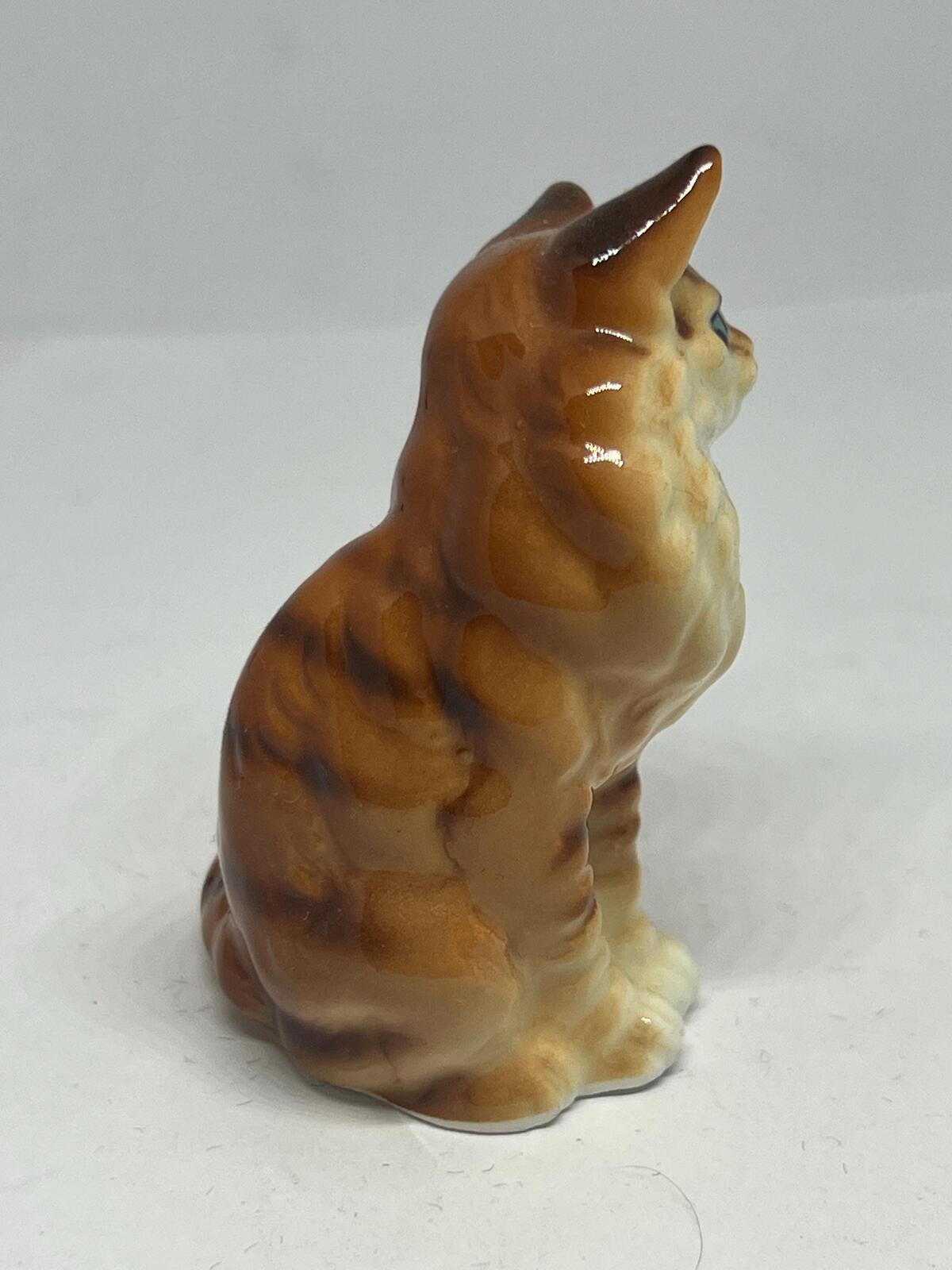 Miniature hand-painted porcelain cat figurine with blue eyes and a tabby calico pattern.