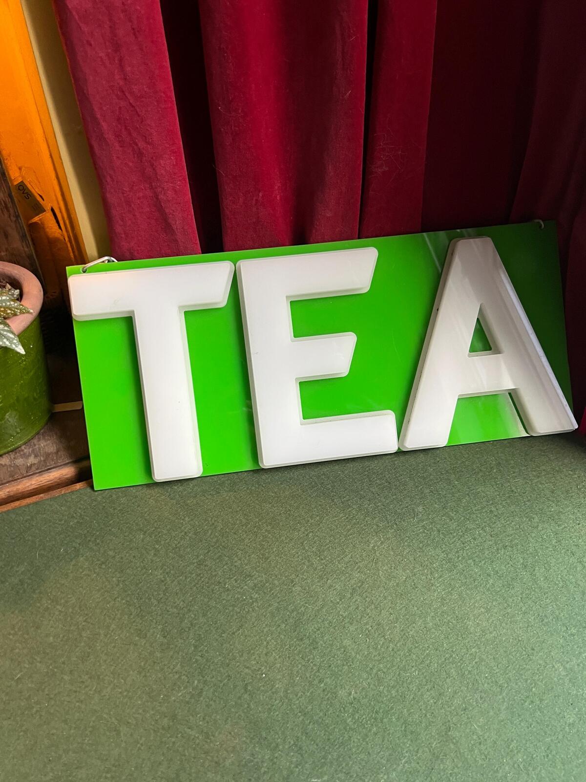 Vintage plastic TEA sign. White plastic letters on neon green background. Silver metal hanging chain.