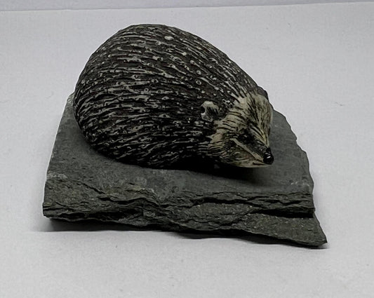 Sculpted hedgehog figurine on a slate base.