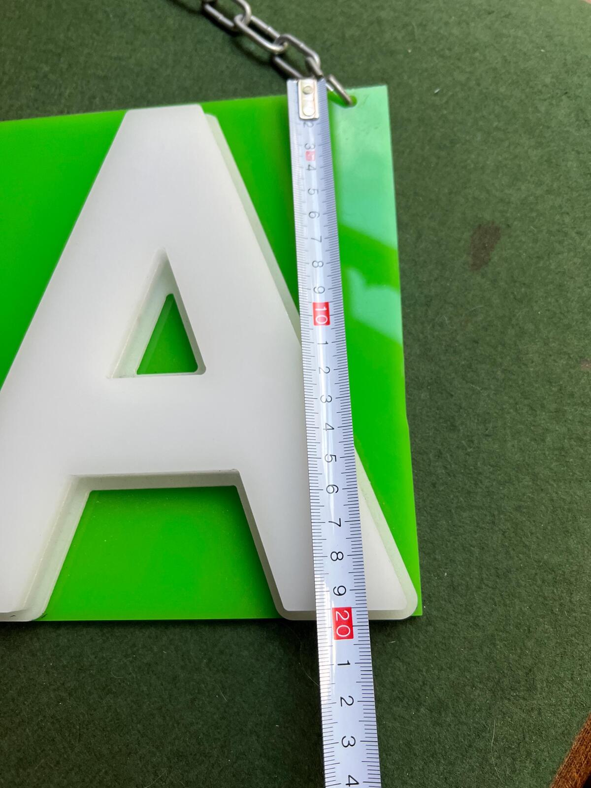 Vintage plastic TEA sign. White plastic letters on neon green background. Silver metal hanging chain.