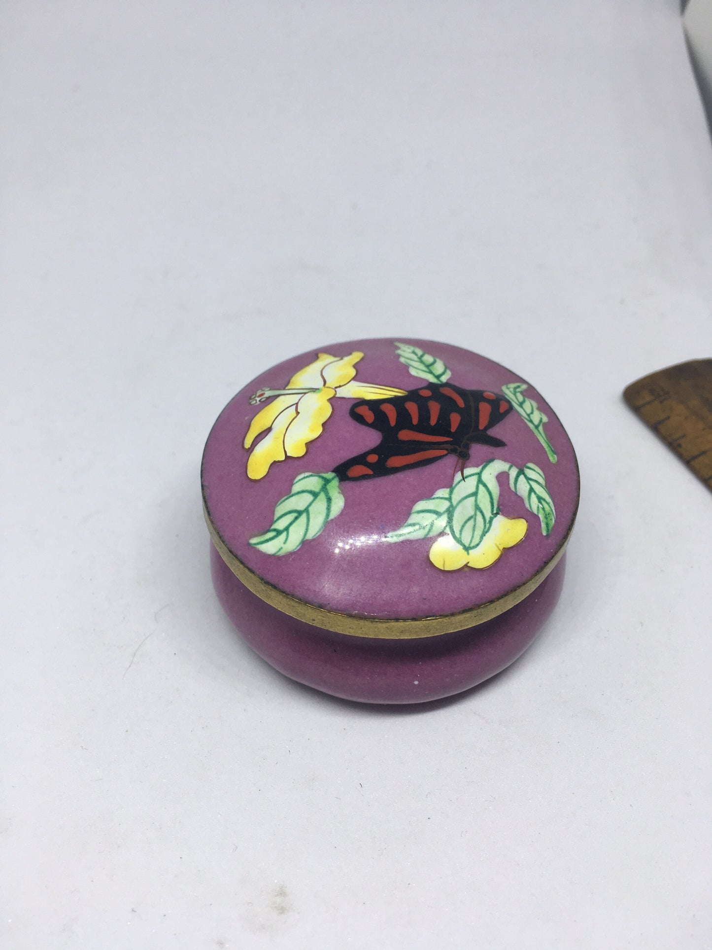 Enamel cloisonne lidded trinket box. Purple enamel with butterfly and flower decoration.