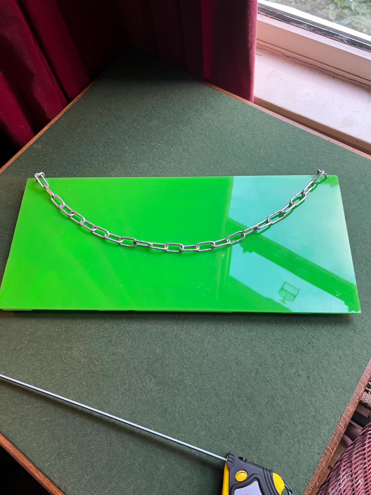 Vintage plastic TEA sign. White plastic letters on neon green background. Silver metal hanging chain.