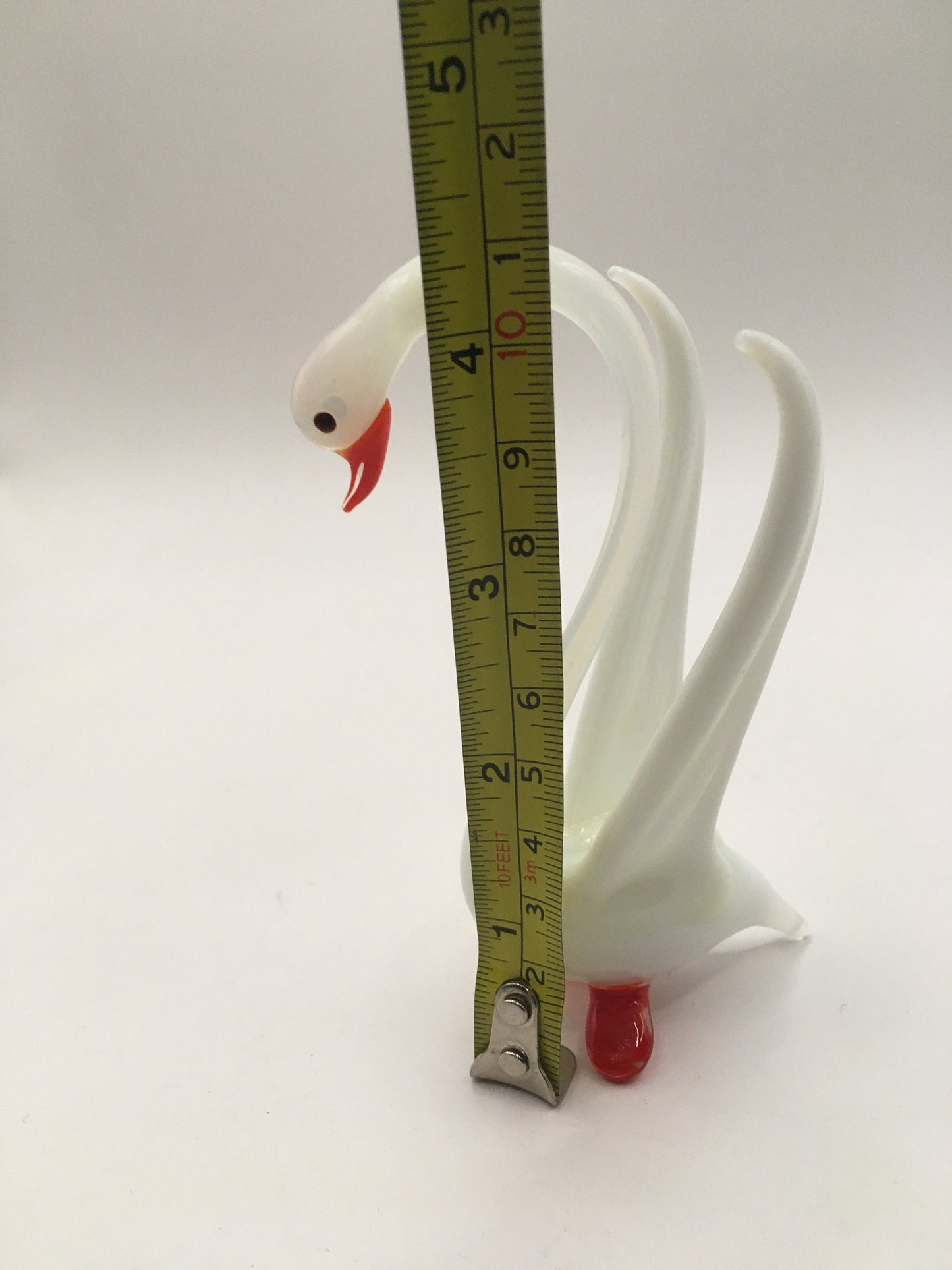 Hand blown art glass long necked white swan figurine with red beak and feet. Wings raised.