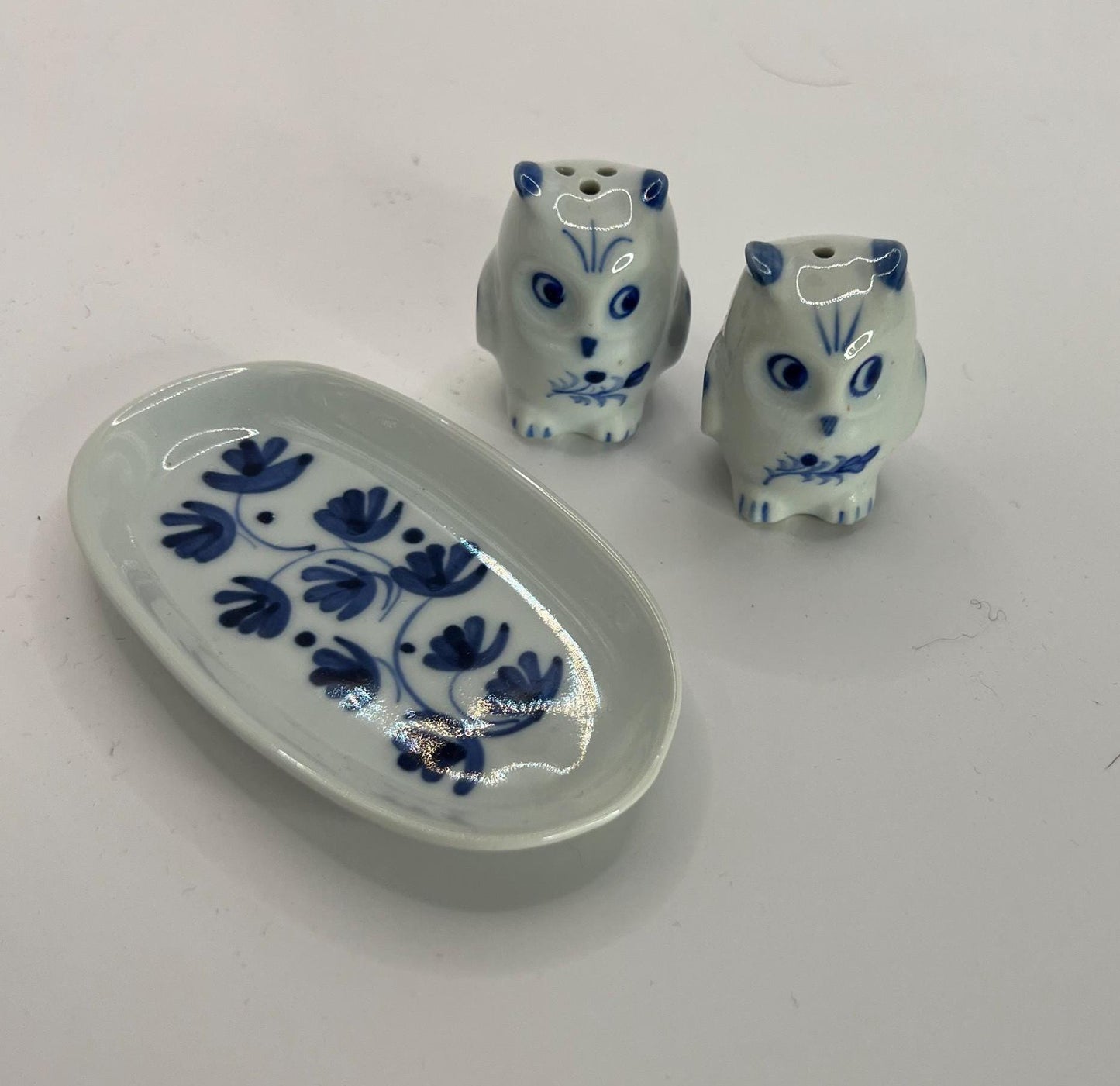 Tiny owl salt and pepper shakers on an oval plate.