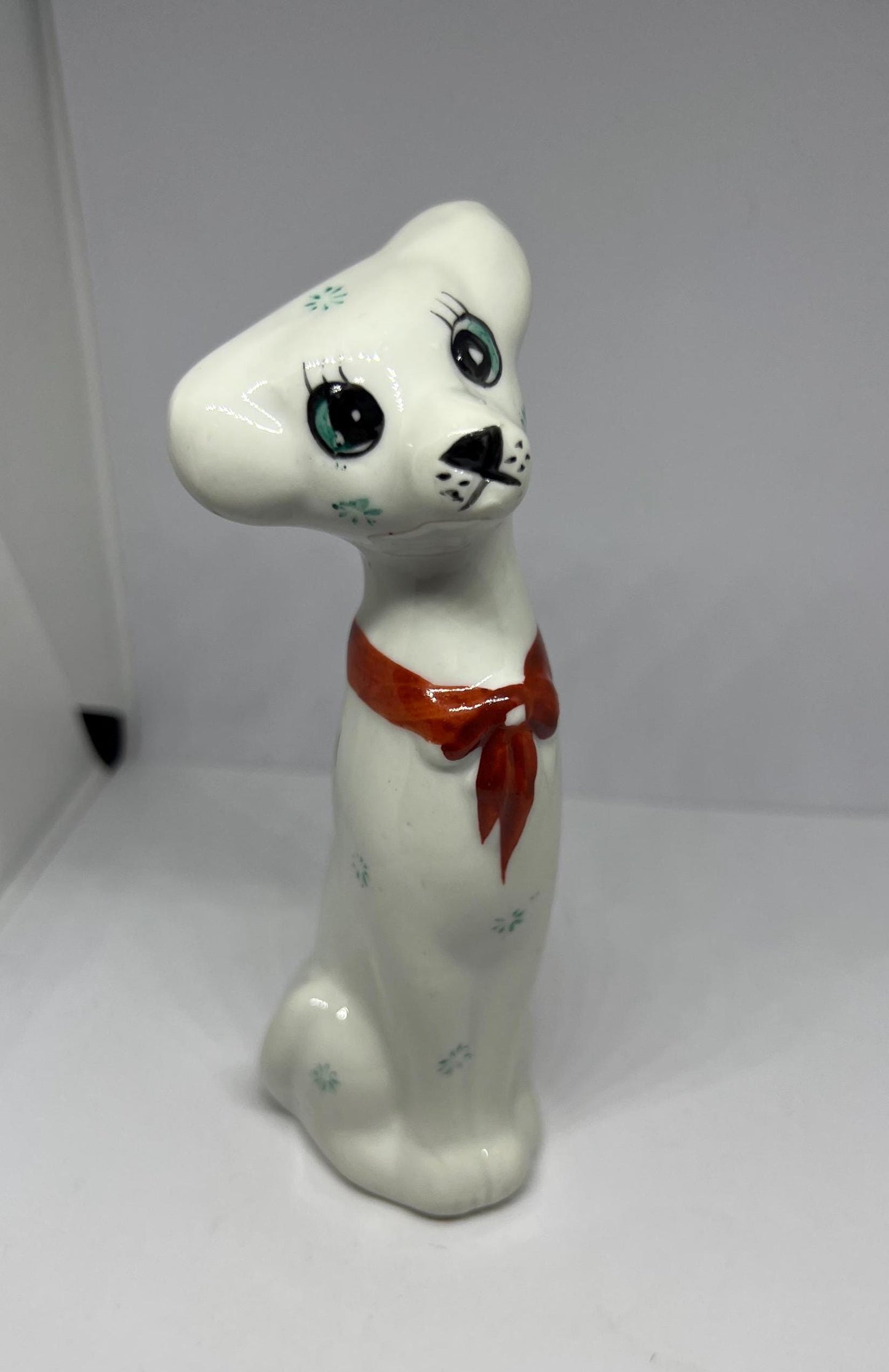 White doe eyed dog with flower spots and red scarf.