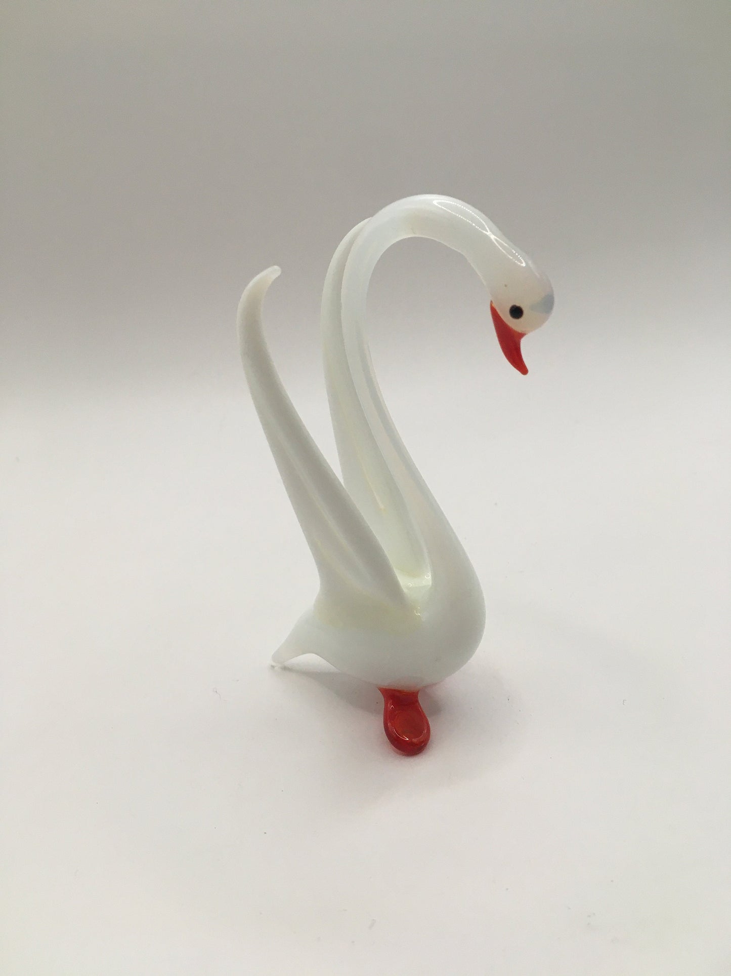 Hand blown art glass long necked white swan figurine with red beak and feet. Wings raised.