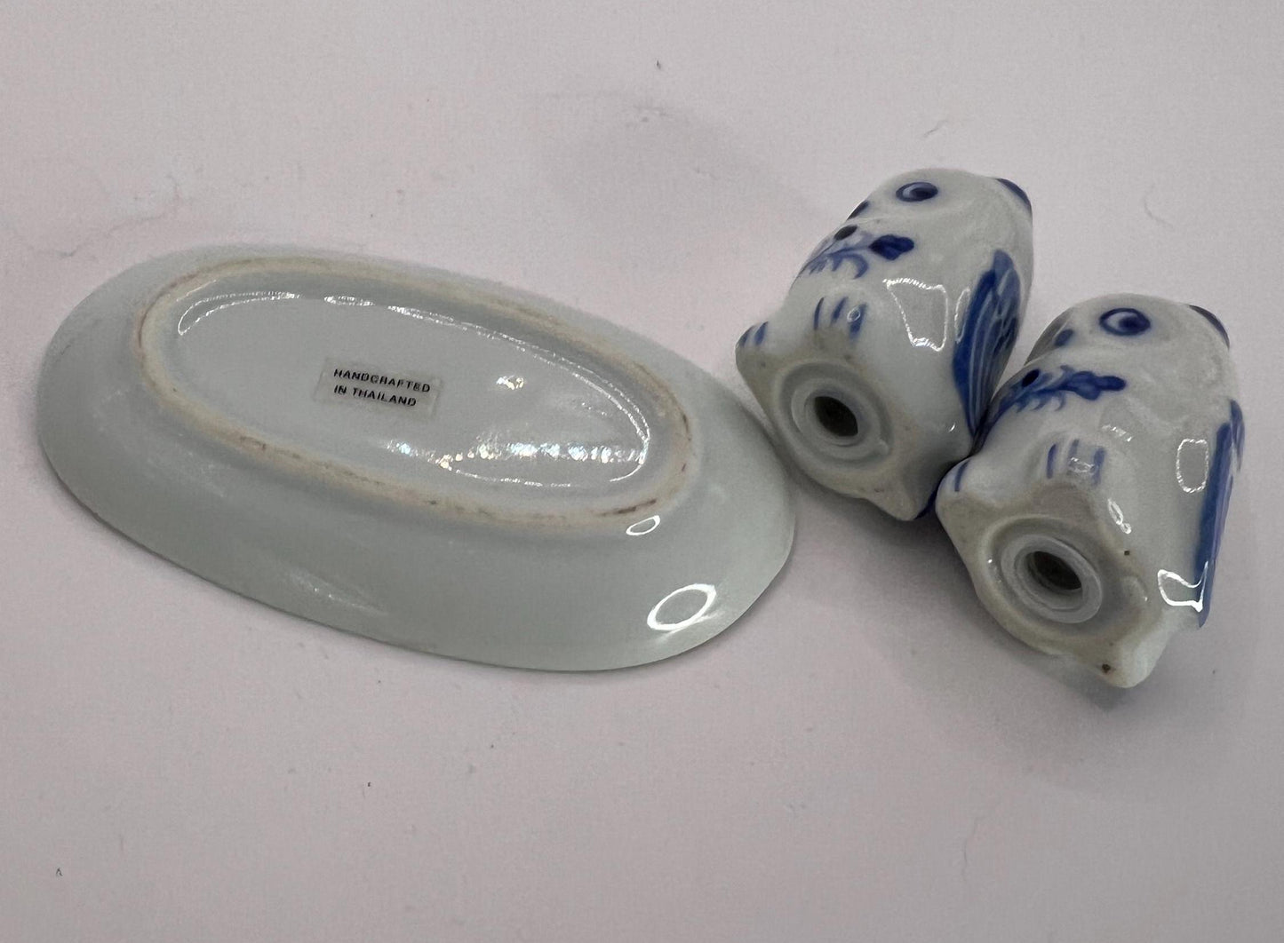 Tiny owl salt and pepper shakers on an oval plate.