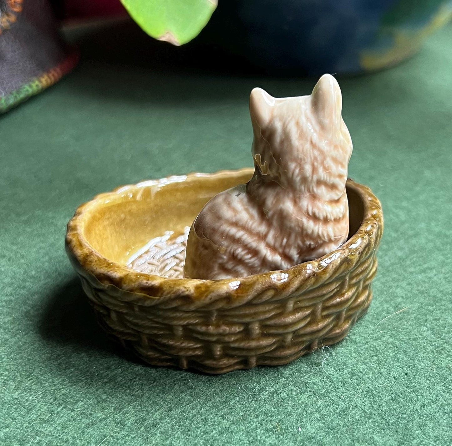 Wade tabby cat sitting in a  green basket.