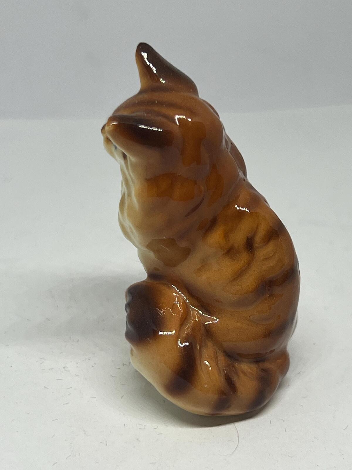 Miniature hand-painted porcelain cat figurine with blue eyes and a tabby calico pattern.