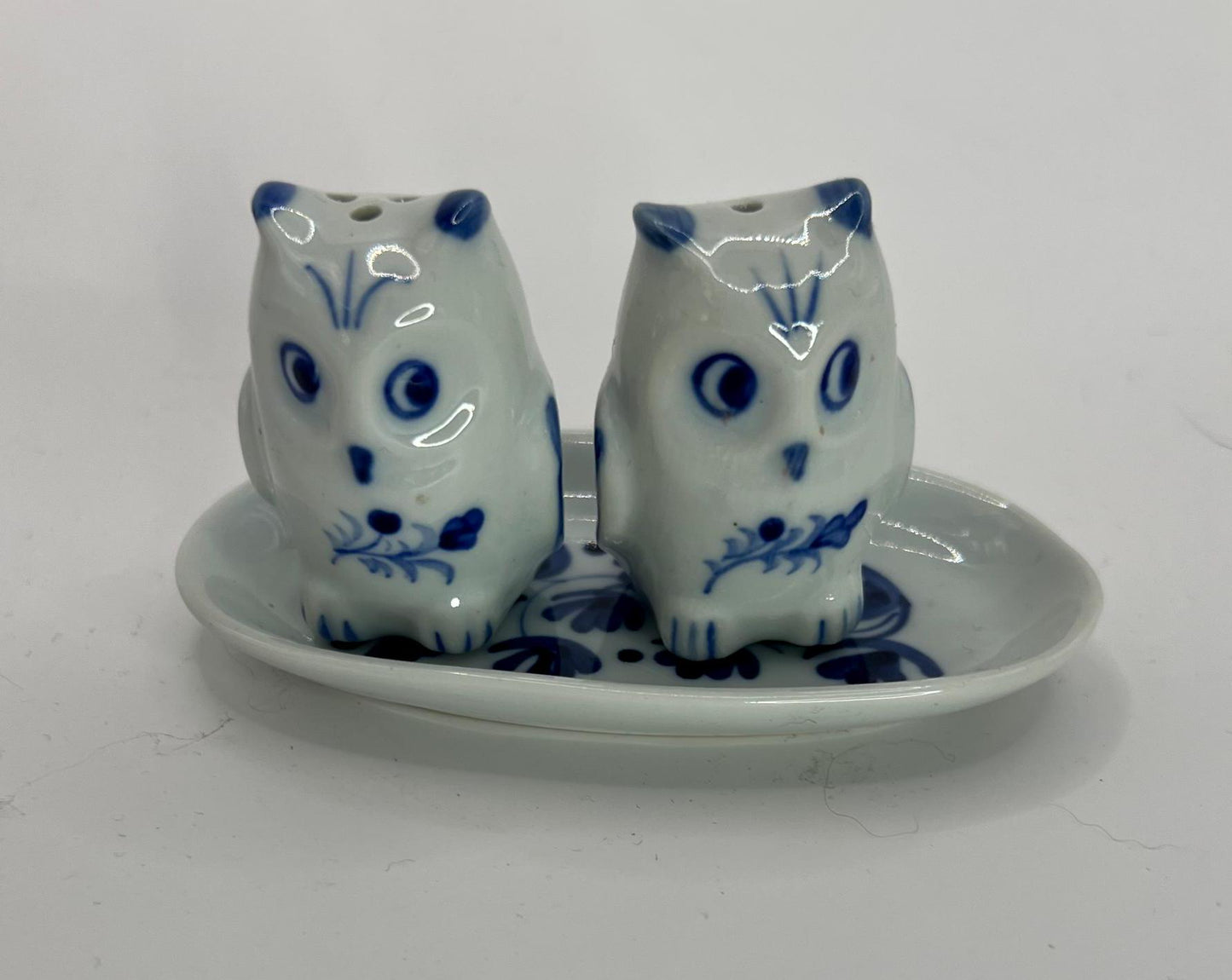 Tiny owl salt and pepper shakers on an oval plate.