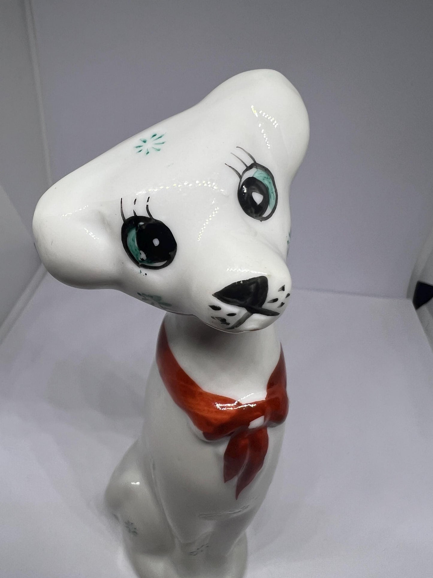 White doe eyed dog with flower spots and red scarf.