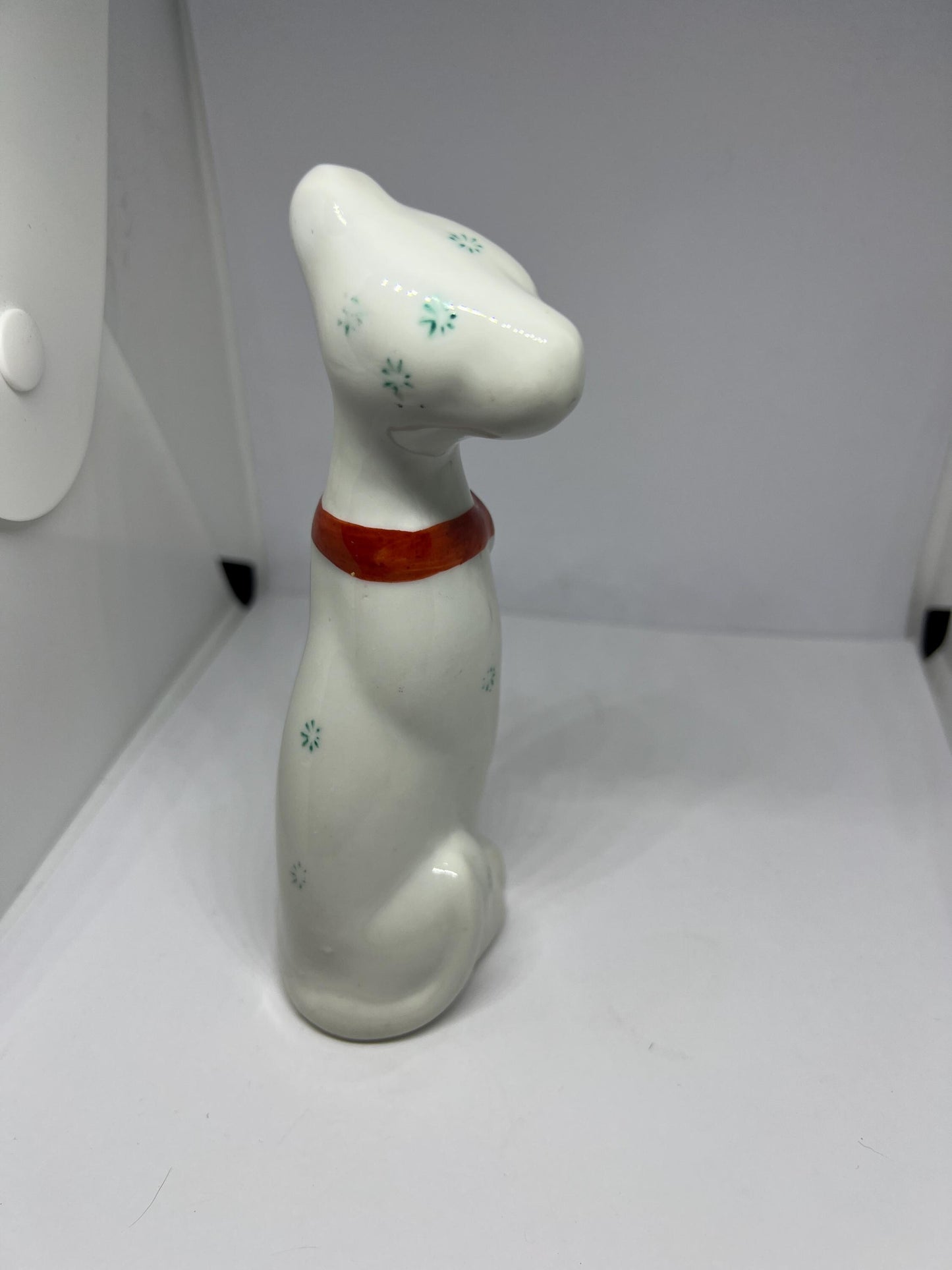 White doe eyed dog with flower spots and red scarf.