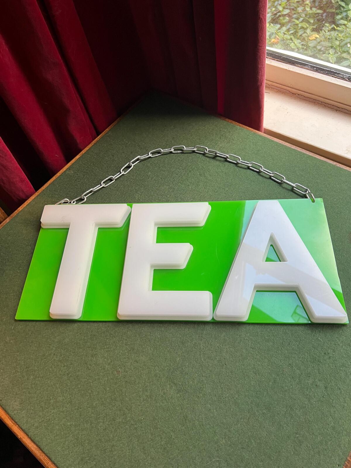 Vintage plastic TEA sign. White plastic letters on neon green background. Silver metal hanging chain.