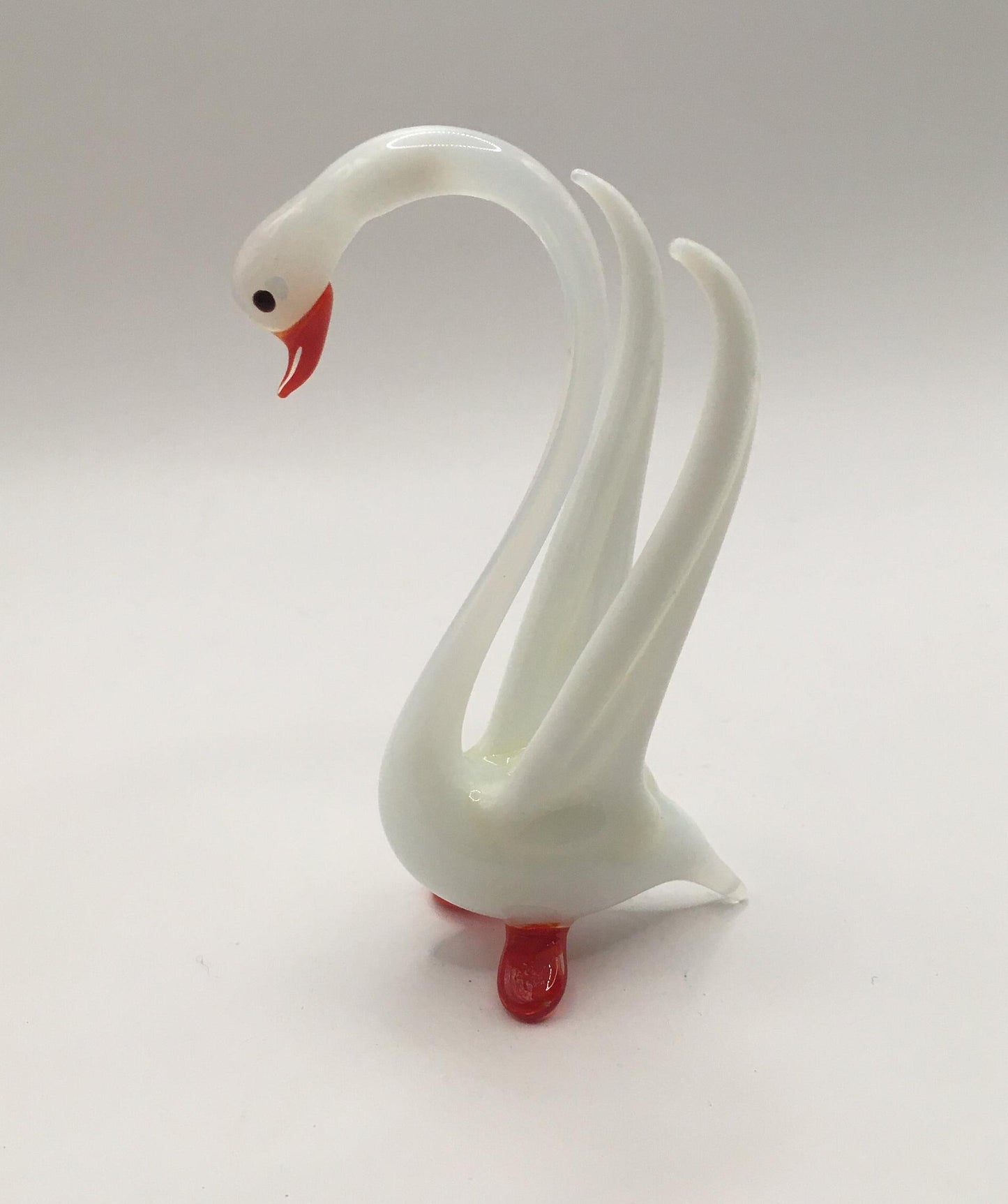 Hand blown art glass long necked white swan figurine with red beak and feet. Wings raised.