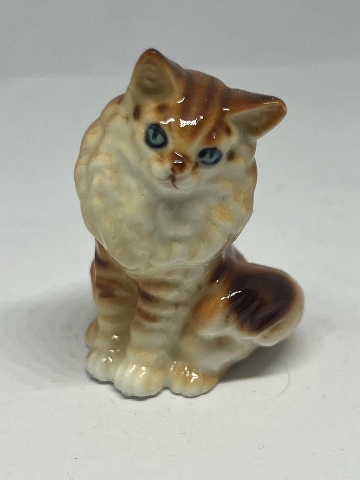 Miniature hand-painted porcelain cat figurine with blue eyes and a tabby calico pattern.